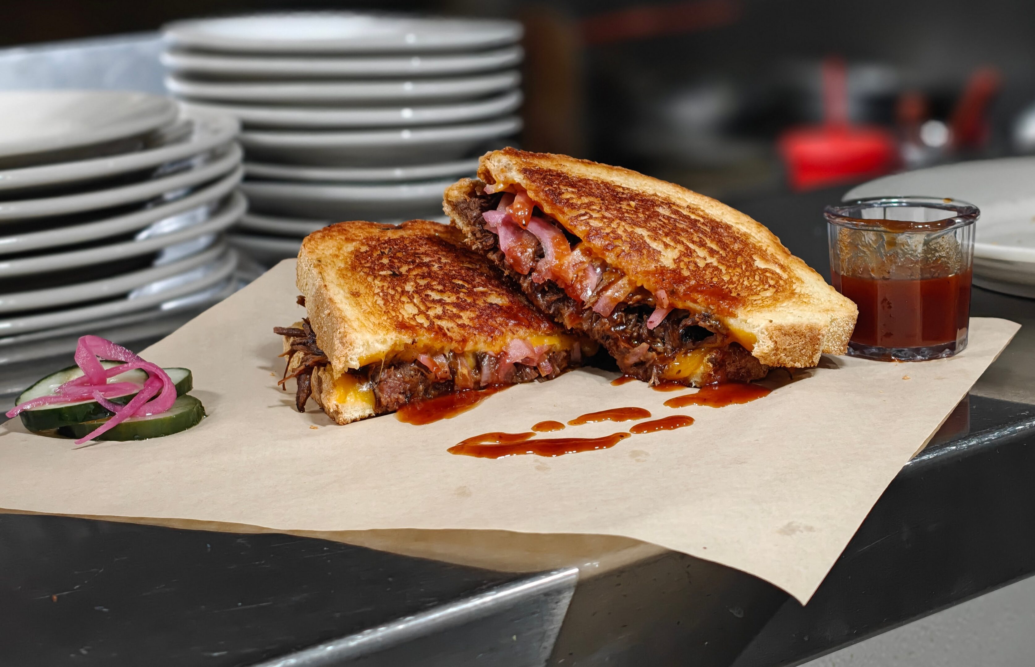 A grilled sandwich filled with meat and sauce, cut in half.