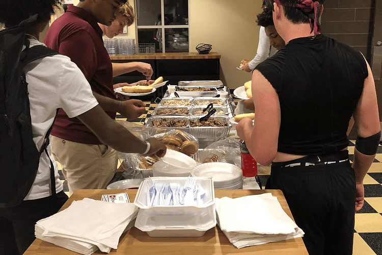 People serving food from a buffet table.