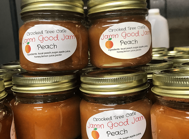 Jars of peach jam stacked on shelf.