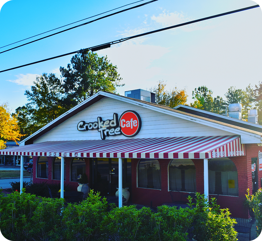 Cafe with striped awning and outdoor seating.
